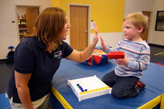 Certified Occupational Therapy Assistant Mikki Patten gives Jake a high five for his successful completion of an eye/hand coordination exercise